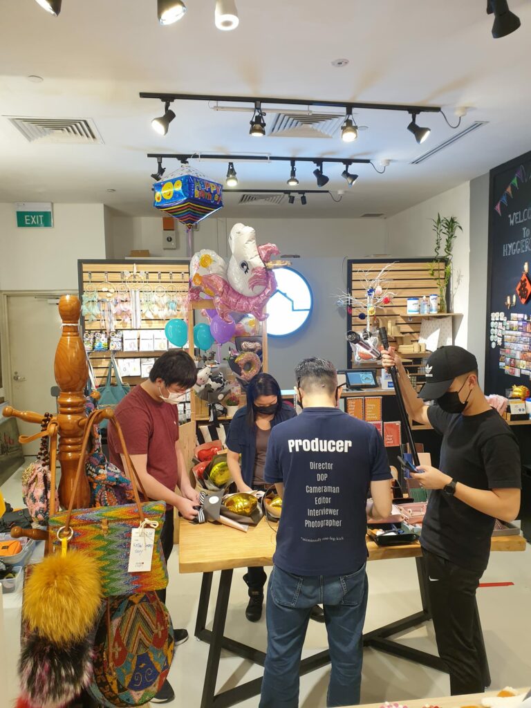 4 people looking down at a bouquet made with a balloon at Inclus’s corporate partner’s store